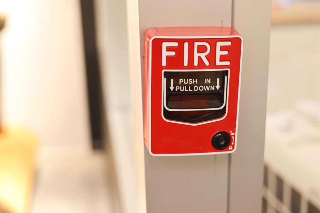 A red fire alarm is mounted on a school wall.