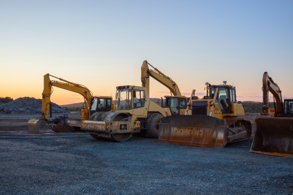 Bulldozers, backhoes, and other heavy equipment sits at the edge of a construction site.