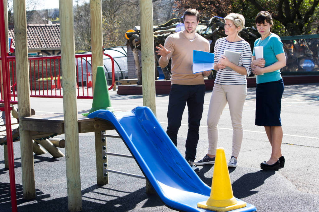 Three technicians use their playground inspection checklists to complete routine maintenance on a playground.